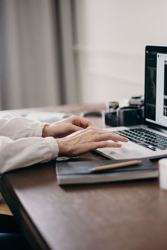 Hands working on a laptop beside product design notes